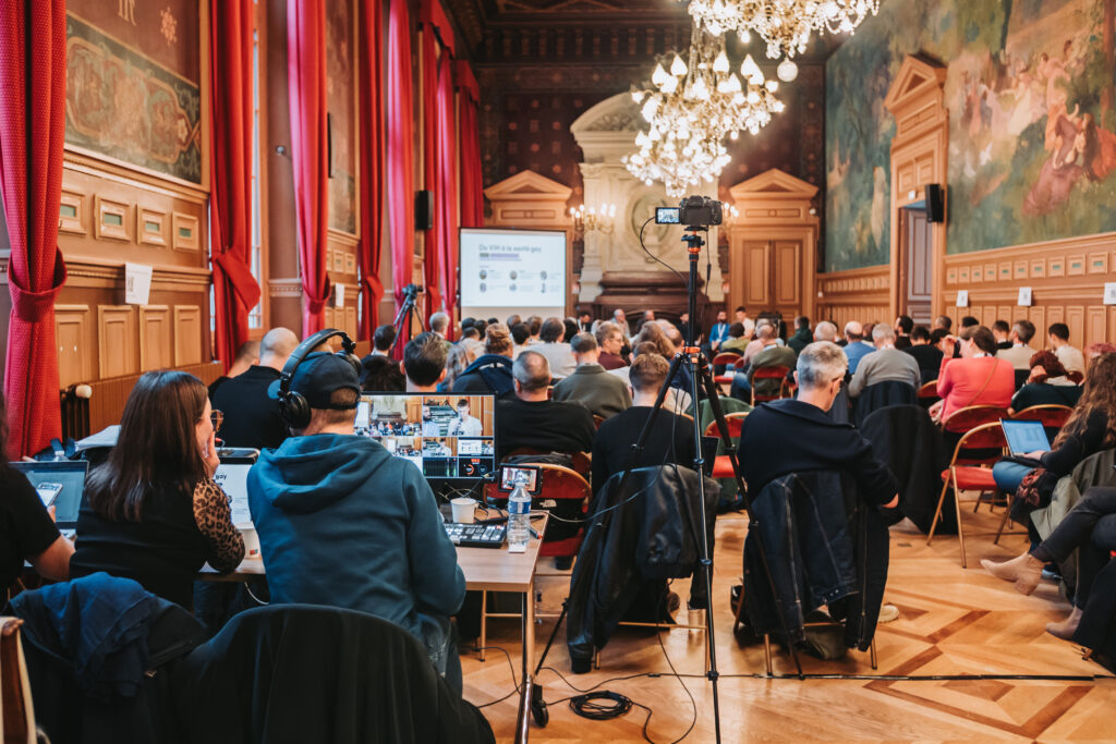 Salle de conférence avec participants attentifs. Il y a un réalisateur avec un client sur une table qui capte la conférence