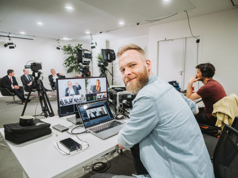 un réalisateur qui regarde la caméra, il fait une captation vidéo d'une conférence